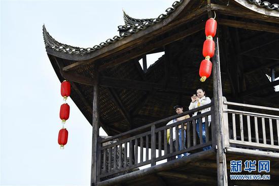  游客在重慶市武隆區(qū)黃鶯鄉(xiāng)復(fù)興村的觀景樓上欣賞田園景色（2019年3月28日攝）。 新華社記者 劉潺 攝